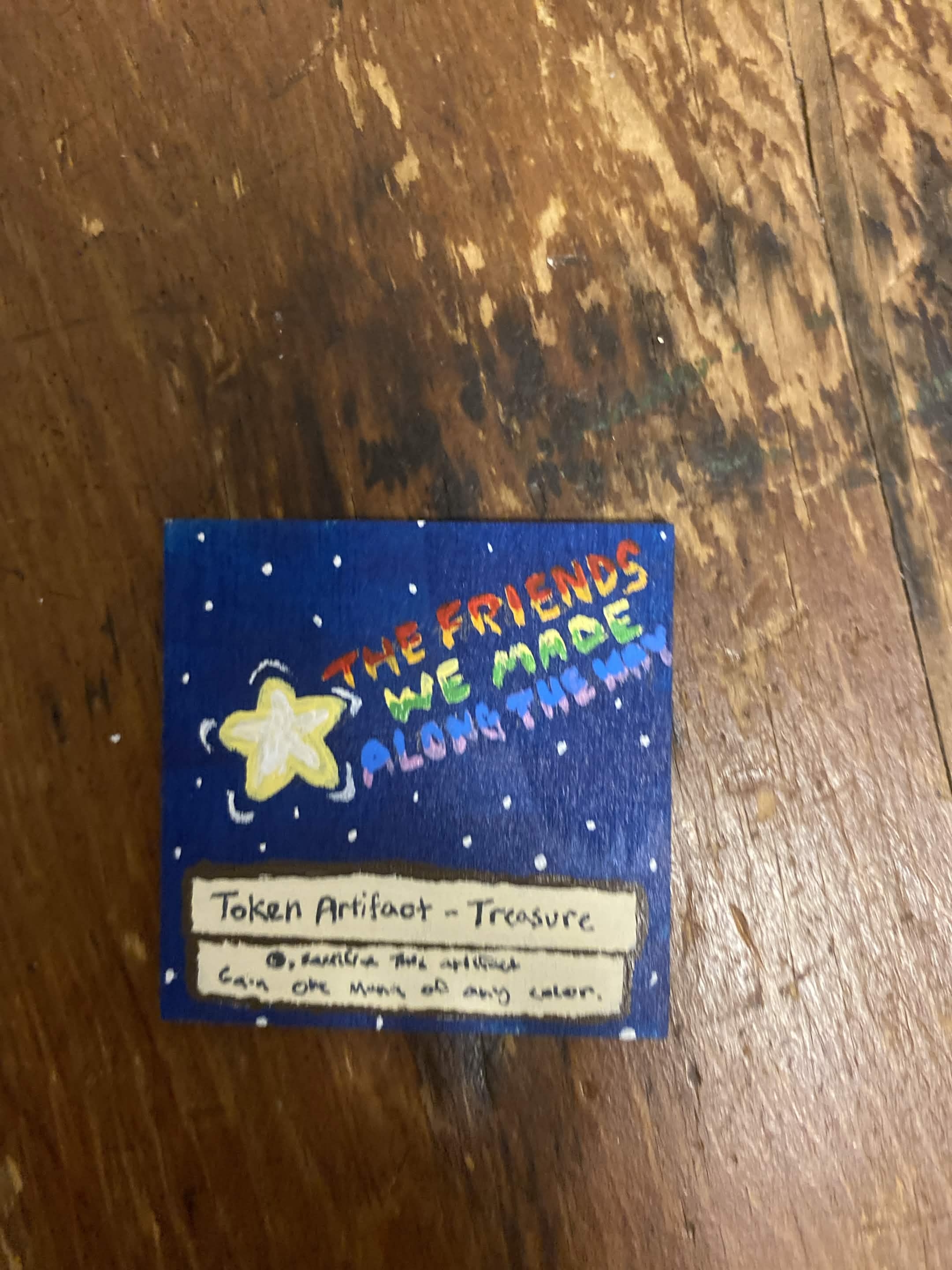 shooting star, rays spell out 'the friends we made along the way'. Text is the same as a Magic the Gathering treasure token