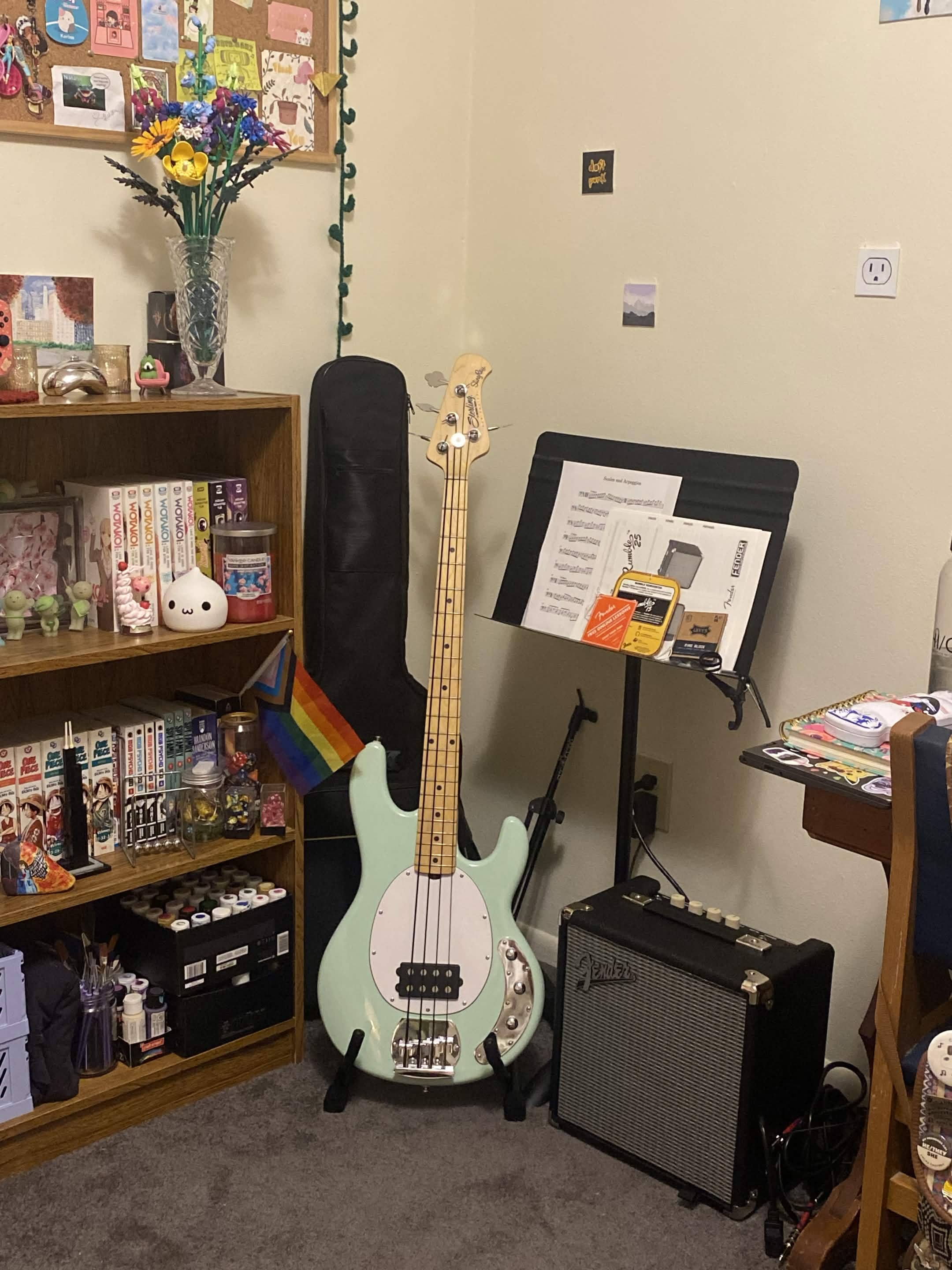 light blue bass guitar stands in corner by bookshelf